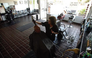 Michele Casco gives a haircut to Charlie Iantosca of Denville at the Family Barber Shop on Broadway in Denville. The shop is still without power but used generators as residents and business owners in Denville, NJ start the cleaning and recovery process after Hurricane Irene flooded the downtown area._8/31/11_STAFF PHOTOGRAPHER/BOB KARP_2011 / staff photo